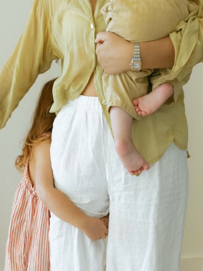 A mother holding her baby, an older child at her side