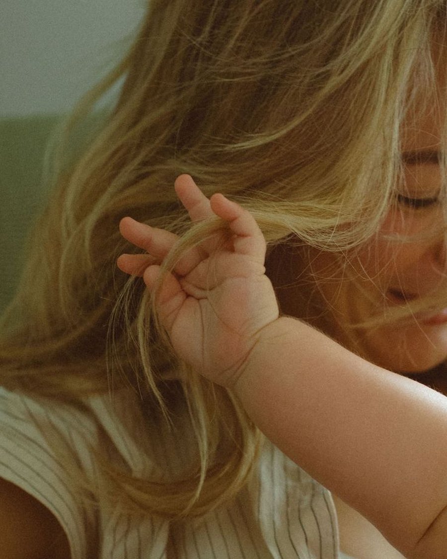 A baby&rsquo;s hand in her mother&rsquo;s hair
